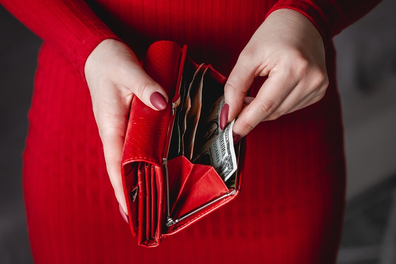 Red wallet in the hands of a woman in a red dress with red manicure