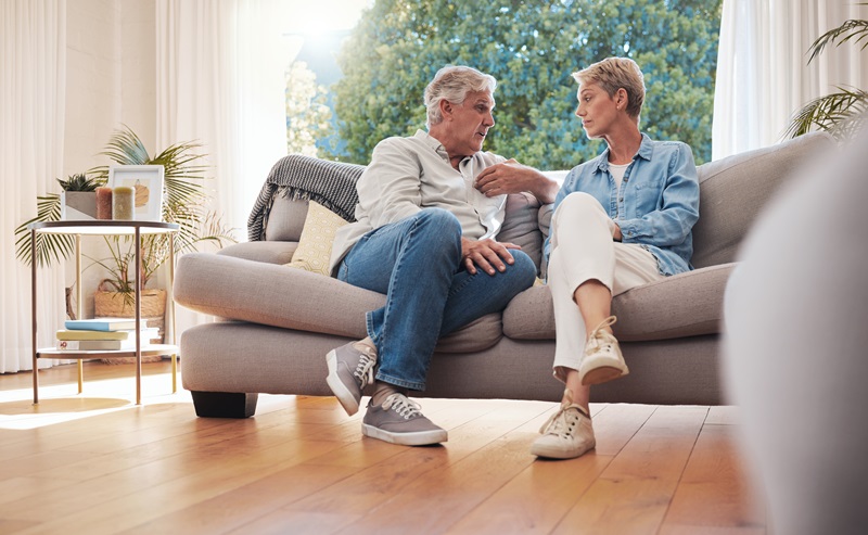 Senior couple, serious talk and communication about problems and marriage issues while sitting on the sofa at home. Mature man and woman talking and discussing issues, trouble and divorce.